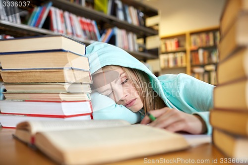 Image of student or woman with books sleeping in library