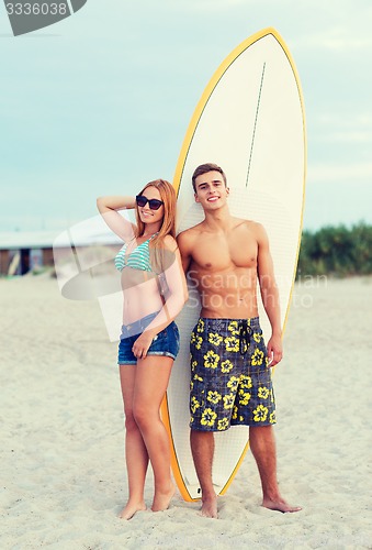 Image of smiling couple in sunglasses with surfs on beach