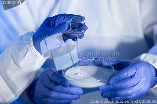Image of close up of scientists hands with chemicals in lab