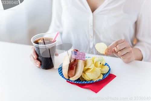 Image of close up of woman eating chips, hot dog and cola