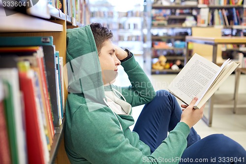 Image of student boy or young man reading book in library