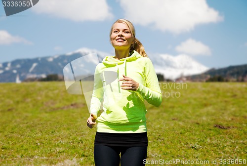 Image of happy young smiling woman jogging outdoors