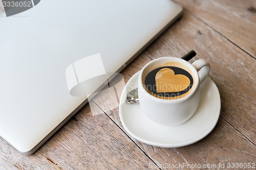 Image of close up of laptop and coffee cup with heart shape