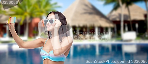 Image of woman in swimsuit taking selfie with smatphone