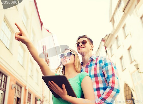 Image of smiling couple with tablet pc in city