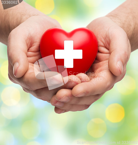 Image of male hands holding red heart with white cross