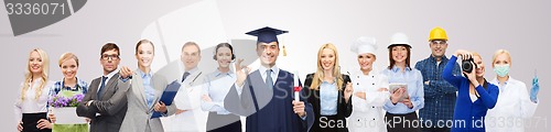 Image of happy bachelor with diploma over professionals