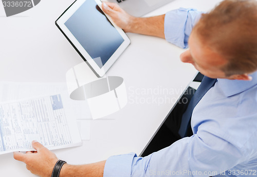 Image of businessman with tablet pc and papers in office