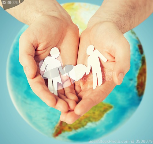 Image of human hands holding paper couple over earth globe