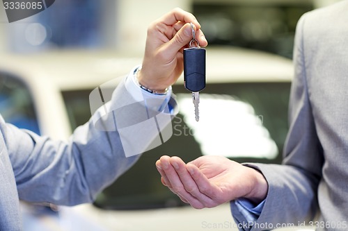 Image of close up of male hands with car key in auto salon