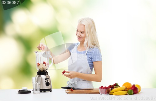 Image of smiling woman with blender preparing shake