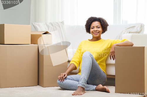 Image of happy african woman with cardboard boxes at home