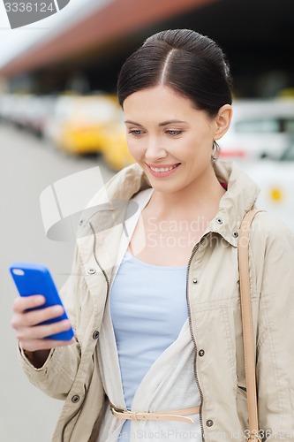 Image of smiling woman with smartphone over taxi in city