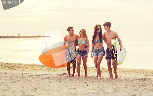 Image of smiling friends in sunglasses with surfs on beach