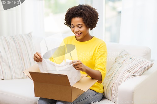 Image of happy african young woman with parcel box at home