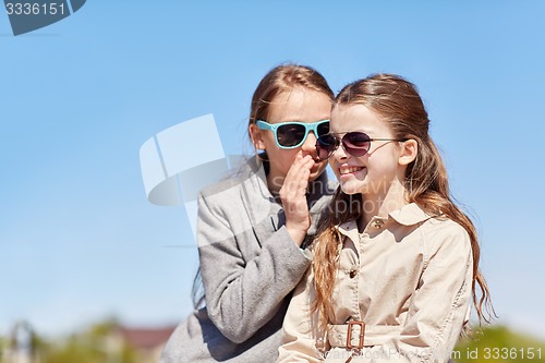 Image of happy girl whispering secret to her friends ear