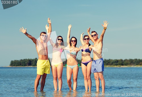 Image of smiling friends in sunglasses on summer beach