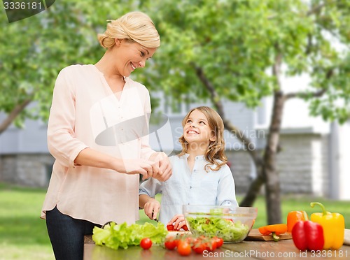 Image of happy family cooking vegetable salad for dinner
