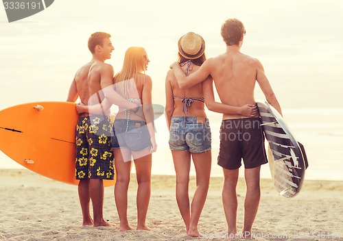 Image of smiling friends in sunglasses with surfs on beach