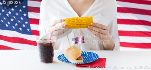 Image of woman hands holding corn with hot dog and cola