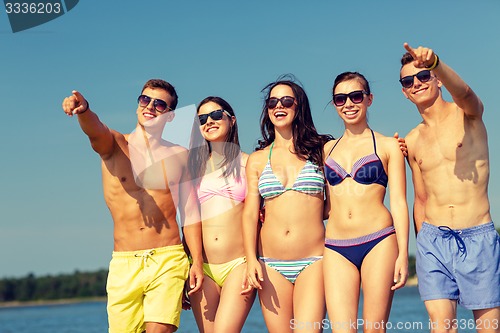 Image of smiling friends in sunglasses on summer beach