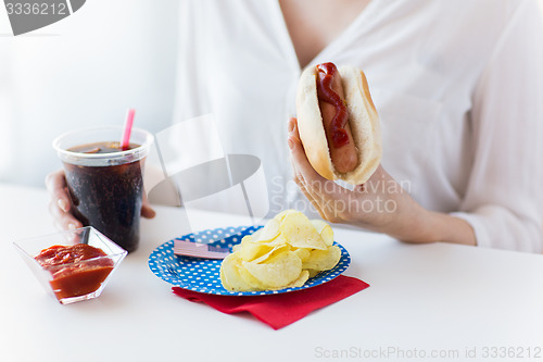 Image of close up of woman eating hot dog with coca cola