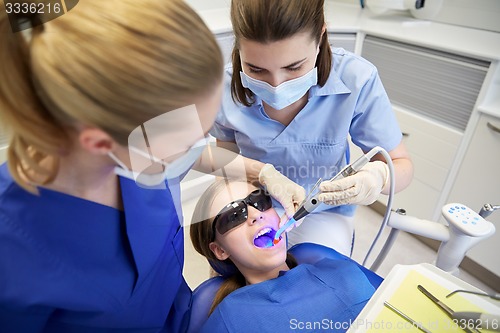 Image of female dentists treating patient girl teeth