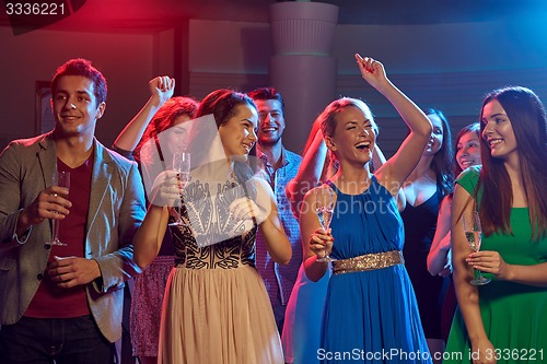 Image of happy friends with glasses of champagne in club