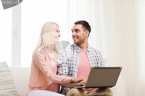Image of smiling happy couple with laptop computer at home