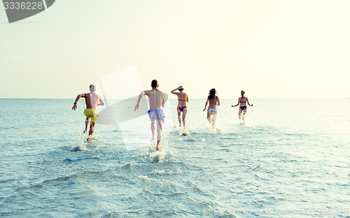 Image of smiling friends running on beach from back