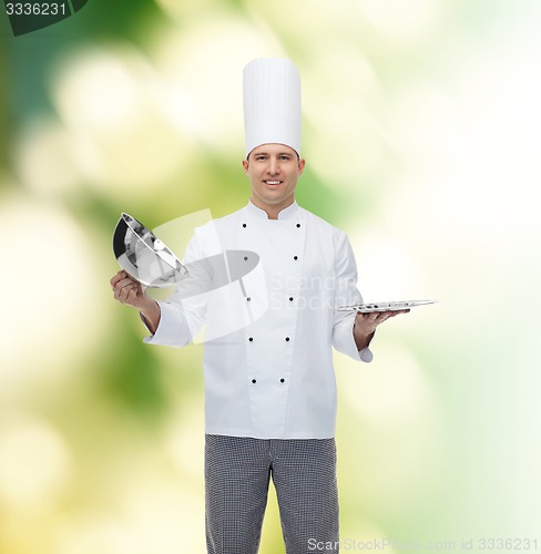 Image of happy male chef cook opening cloche