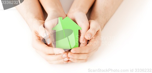 Image of man and woman hands with green paper house