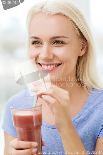 Image of smiling woman drinking juice or shake at home