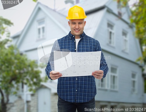 Image of smiling builder with blueprint over house