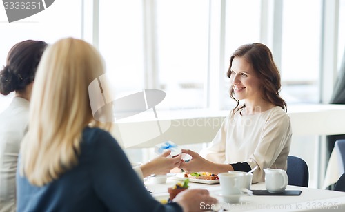 Image of happy women giving birthday present at restaurant