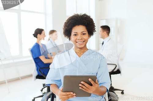 Image of happy nurse with tablet pc over team at hospital