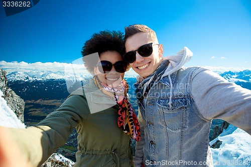 Image of happy teenage couple taking selfie over mountains