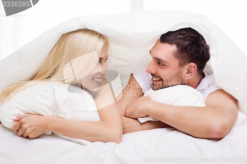 Image of happy couple lying in bed and talking at home