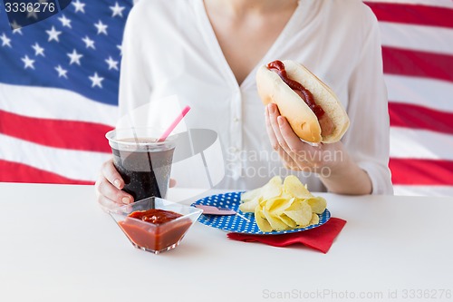 Image of close up of woman eating hot dog with coca cola