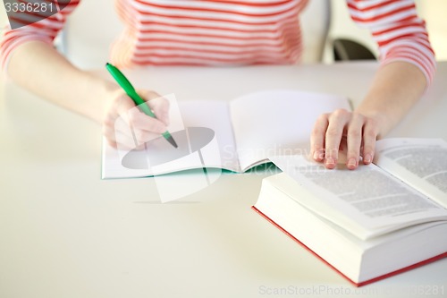 Image of close up of female hands with book and notebook