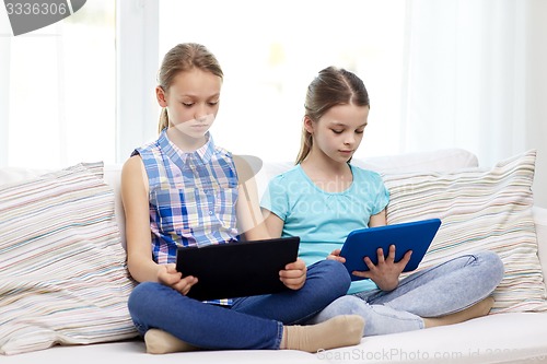 Image of girls with tablet pc sitting on sofa at home