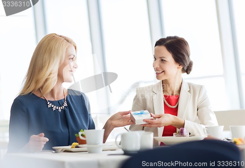 Image of happy women giving birthday present at restaurant