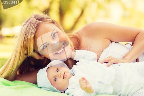 Image of happy mother lying with little baby on blanket