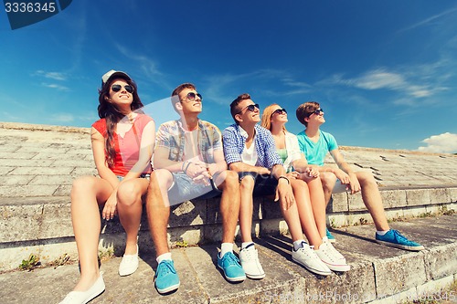 Image of group of smiling friends sitting on city street