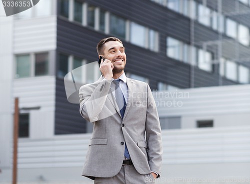 Image of smiling businessman with smartphone outdoors