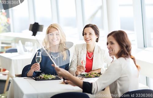 Image of women with smartphone taking selfie at restaurant