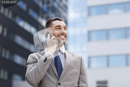 Image of smiling businessman with smartphone outdoors