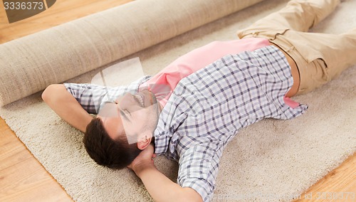 Image of happy man lying carpet or rug at home