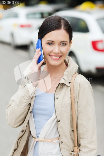 Image of smiling woman with smartphone over taxi in city