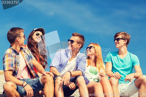 Image of group of smiling friends sitting on city street